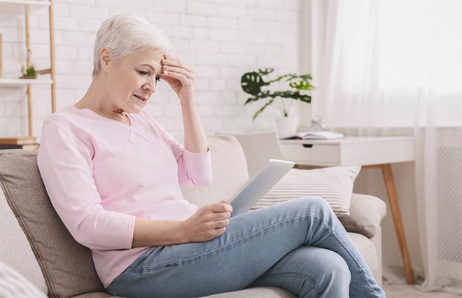 photo - a person sitting down, reading from a tablet device and looking concerned