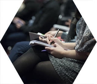 photo - closeup of a crowd sitting in a conference hall, taking notes