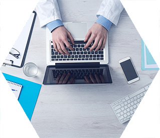 photo - closeup of someone using a laptop seen from above, surrounded by medical equipment