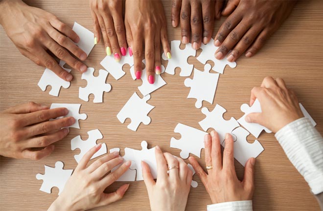 photo - closeup of multiple people working together on a puzzle