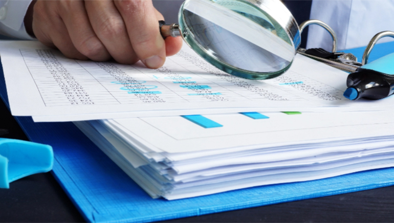 photo - close up of a person reviewing a printed table of data with a magnifying glass
