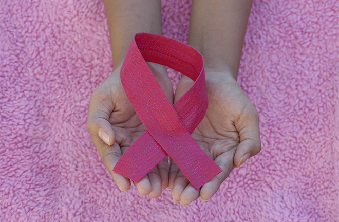 photo - closeup of a pair of hands holding a pink ribbon