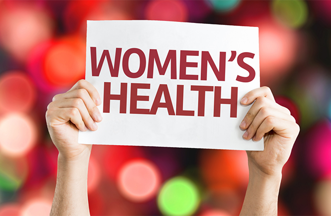 photo - a pair of hands holds up a sign that reads WOMEN'S HEALTH
