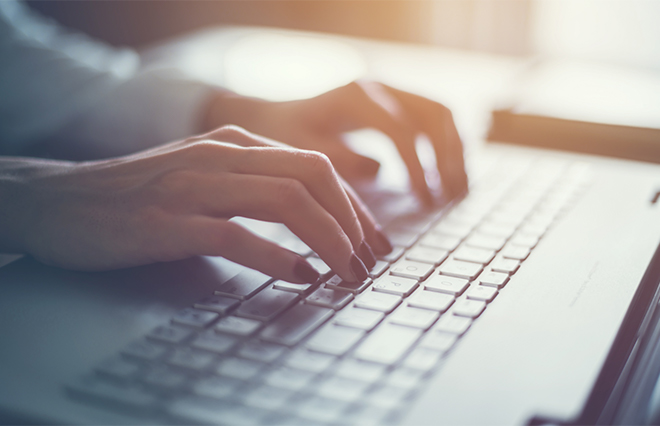 photo - closeup of a pair of hands poised over a computer keyboard