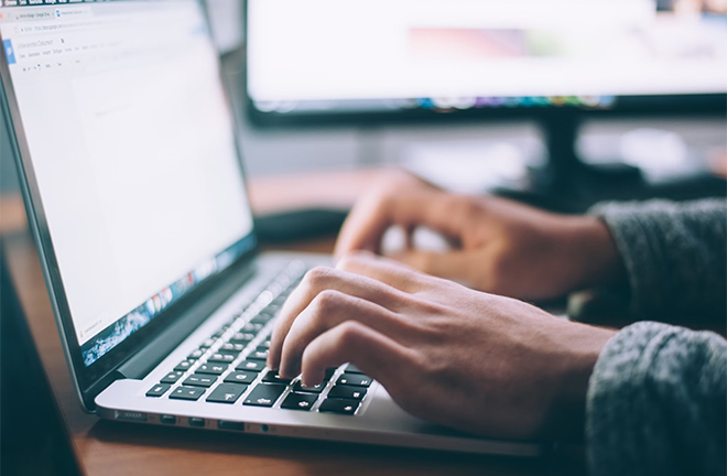 photo - closeup of someone's hands as they use a laptop