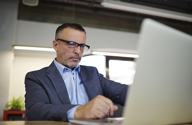 photo - a man wearing a suit uses a laptop