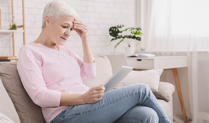 photo - a person sitting down, reading from a tablet device and looking concerned