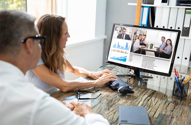 photo - two people look at a computer monitor displaying graphs and photos