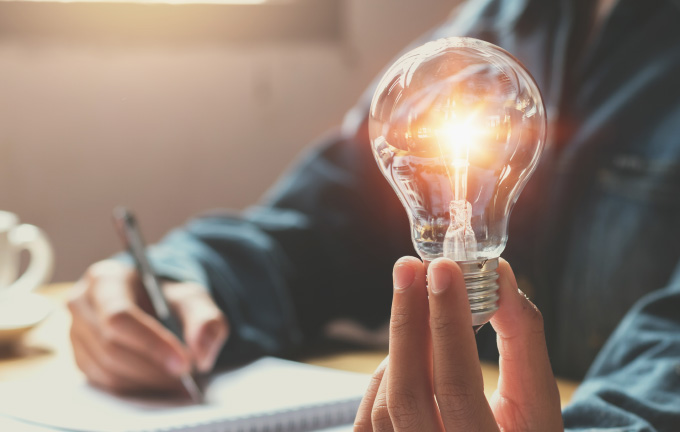 photo – closeup of someone holding a lit lightbulb